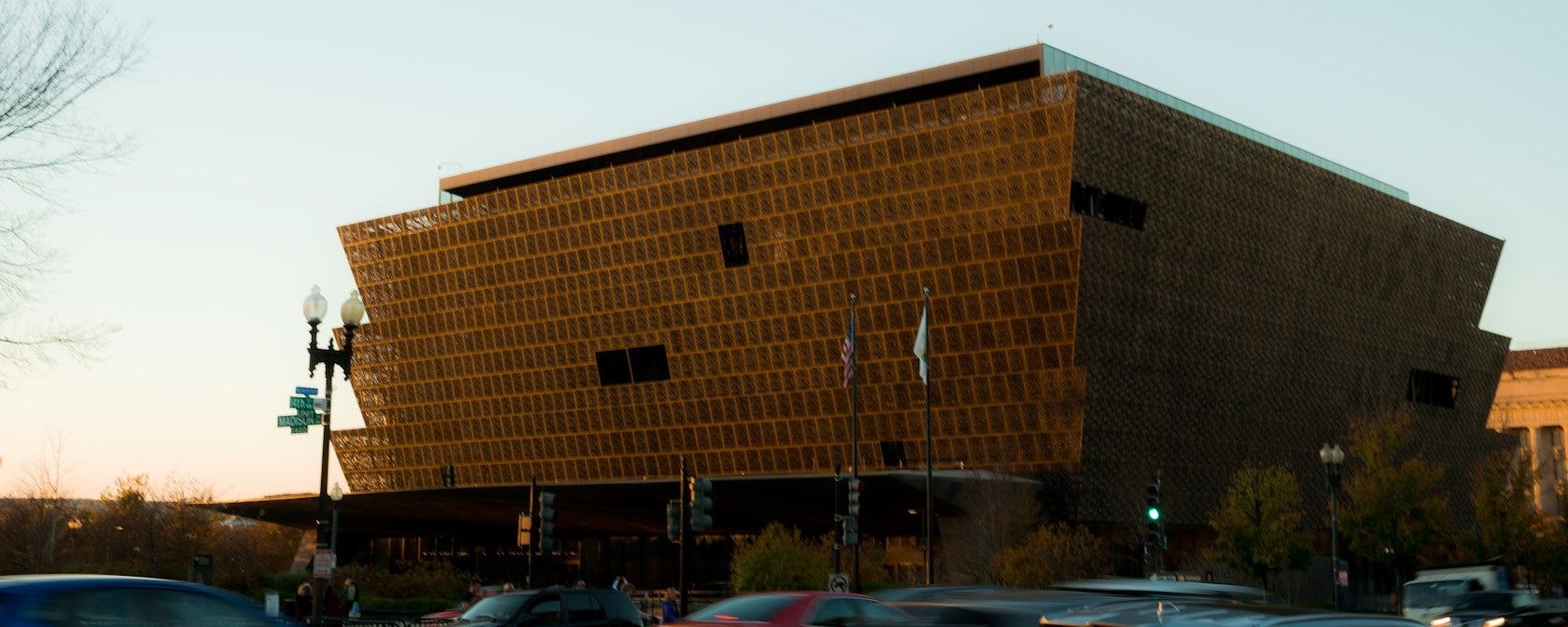 Modern brown building at dusk and traffic passing by
