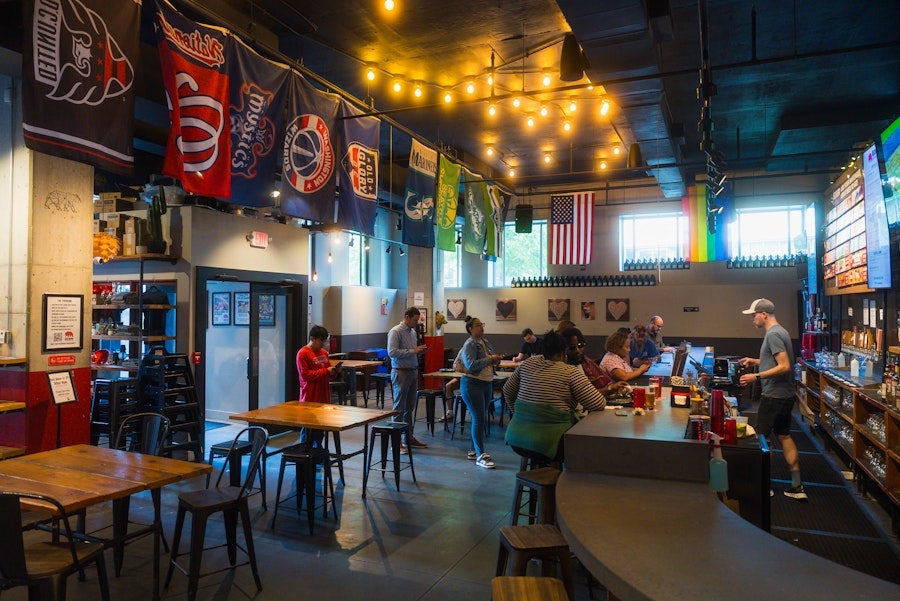 People dining in a cozy brewery with DC and Seattle flags overhead