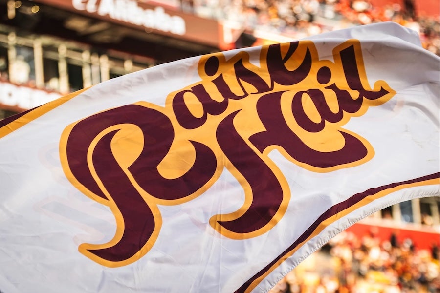 Rally flag waving in stadium crowd, with 'Raise Hail' text in maroon and gold