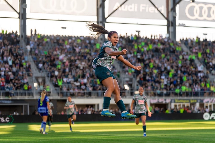 Photo of soccer player celebrating in a packed stadium under bright lights