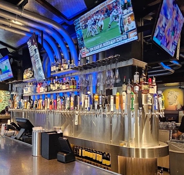 Sports bar with a curved wall of beer taps and big TV screens