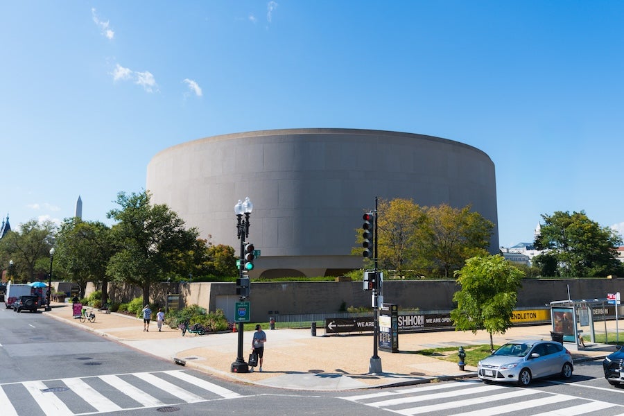 Photo of the Smithsonian Hirshhorn Museum, Washington, DC, with street traffic and crosswalk