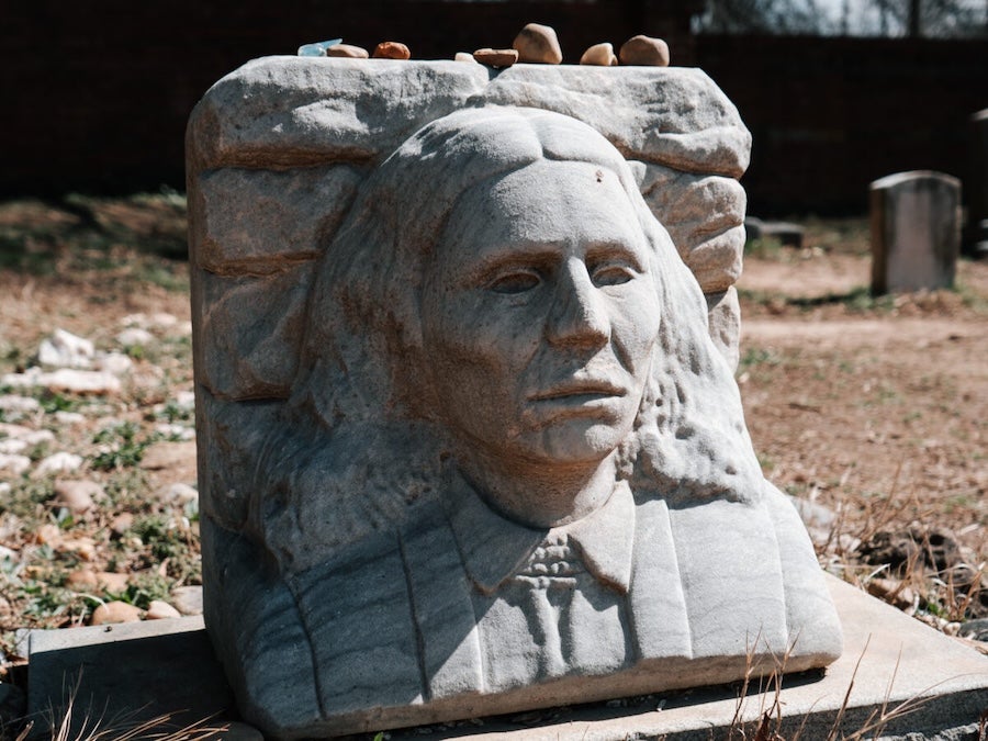 A gravestone bust of a person with long hair at the Historic Congressional Cemetery