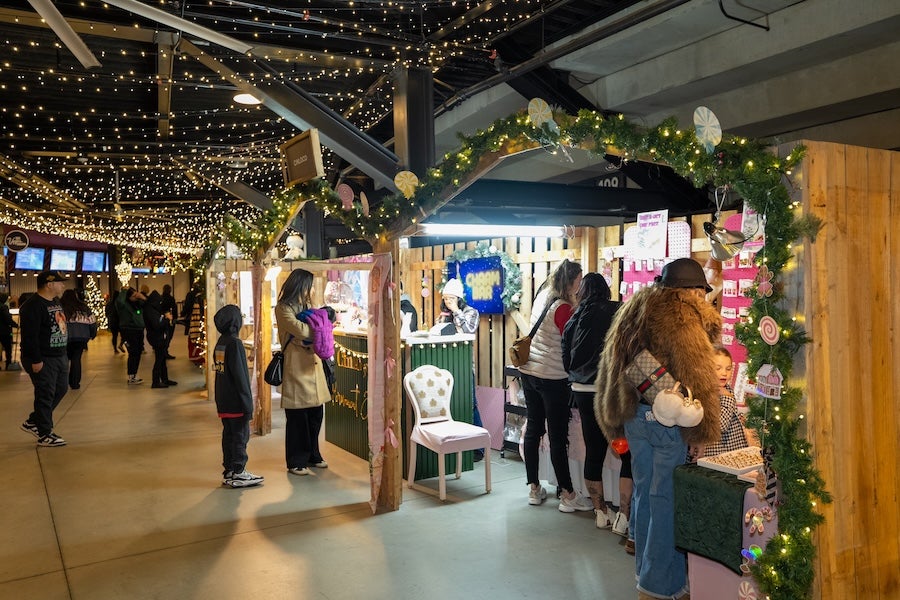 Photo: People browse a festive indoor market under string lights and wreath arch
