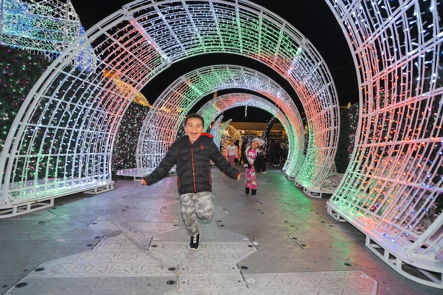 Photo: Person walking through colorful light tunnel at night