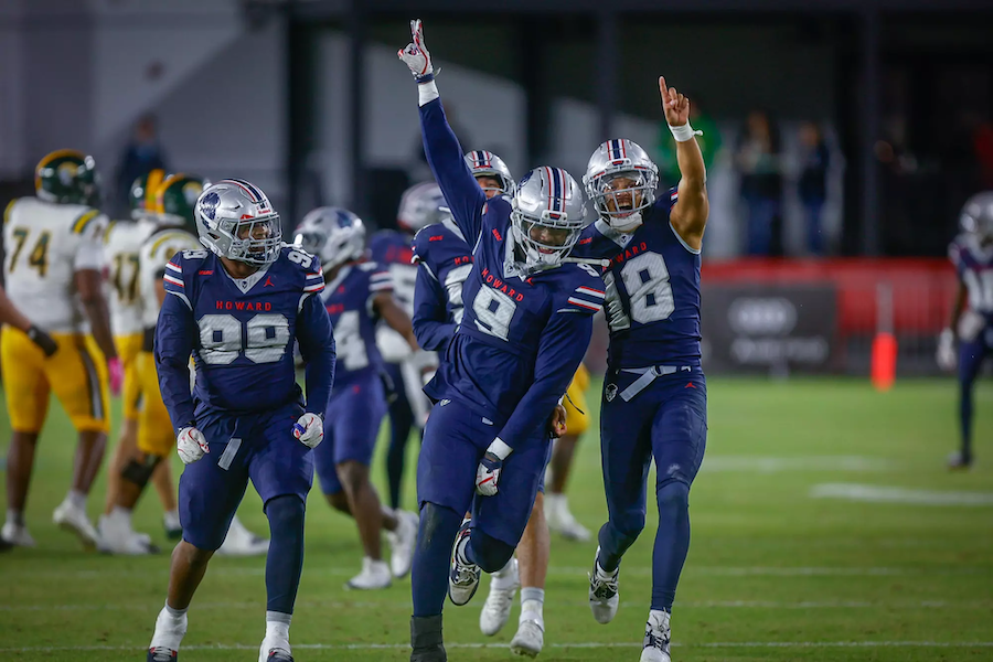 Football players in blue uniforms celebrate on a lit field at night