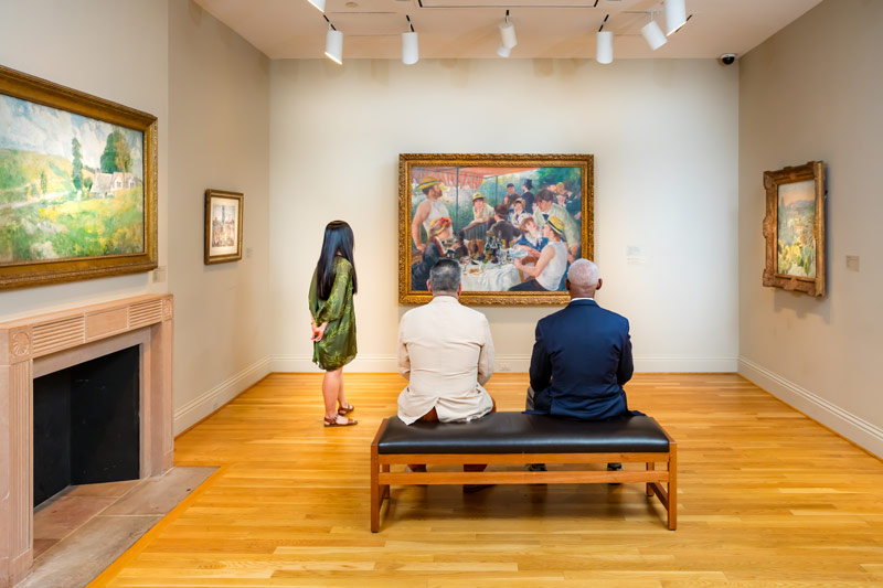 Visitantes que ven el `` Almuerzo de la fiesta en bote '' de Renoir en The Phillips Collection en Washington, DC, el vecindario de Dupont Circle