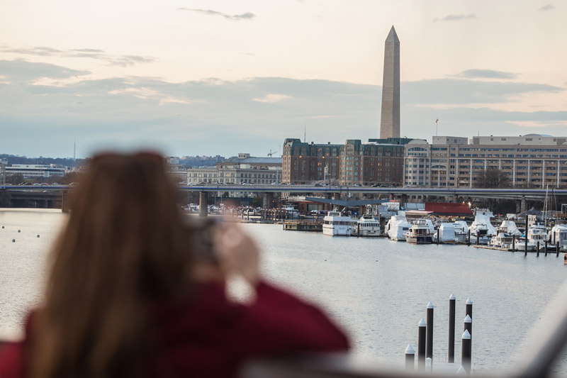 Mujer tomando fotos del Monumento a Washington desde el barco Entertainment Cruises - Actividades de navegación en el agua en Washington, DC
