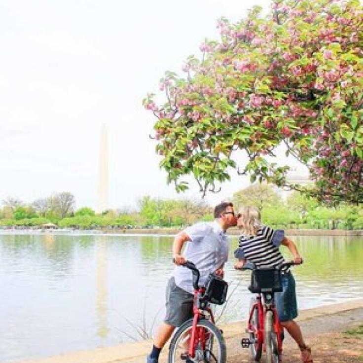 @the.snyder.spot - Husband and wife kissing on bikes in front of the Tidal Basin - Romantic places to visit in Washington, DC