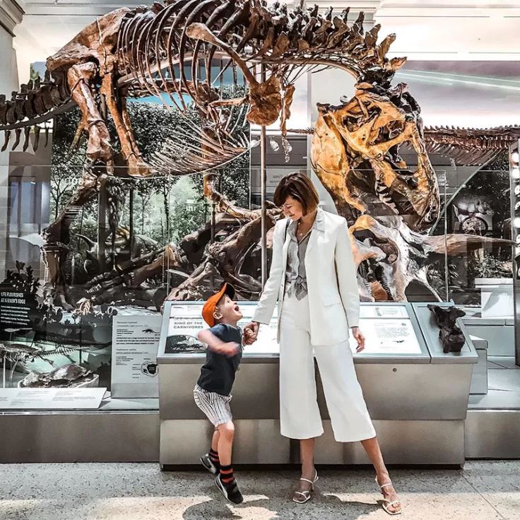Mère et fils debout devant un squelette de dinosaure au Musée national d'histoire naturelle