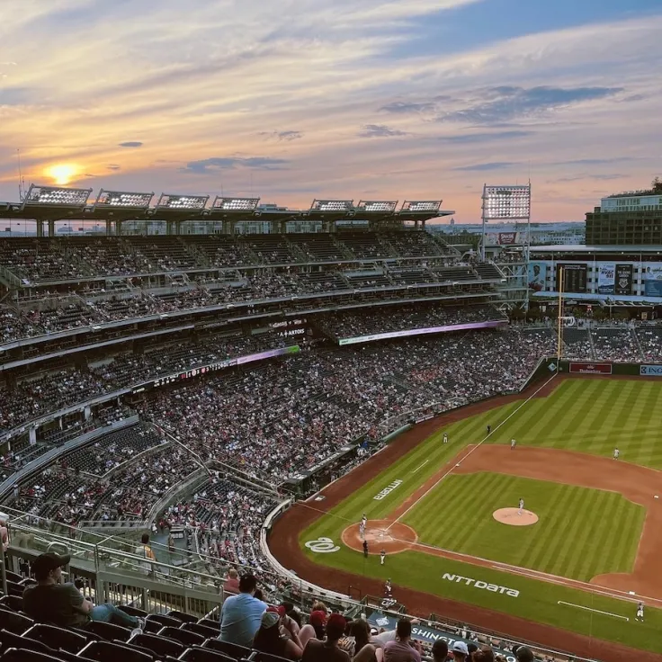 Photo of Nationals Park at sunset, packed crowd watching a baseball game in Washington, DC