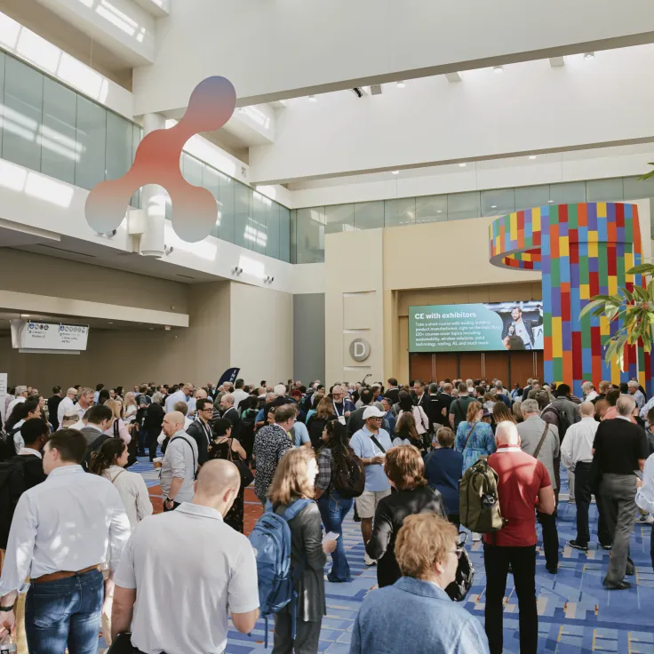 Crowd mingling in bright atrium beneath large red sculpture and colorful flags