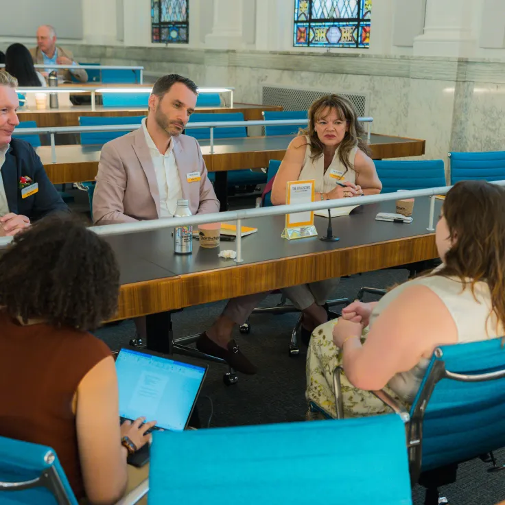 Panelists at table speak to small audience in bright conference room