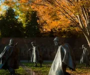 Several figures from the Korean War Veterans Memorial with autumn trees.