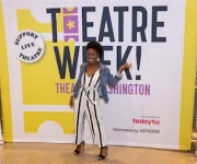Woman posing in front of a Theatre Week banner.