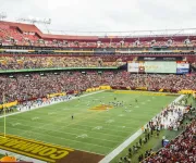 A packed stadium during a Washington Commanders football game, with fans filling the stands and players on the field at FedExField.