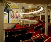 The historic Ford's Theatre features elegant red seating, curved balconies, and a stage framed by rich gold accents.