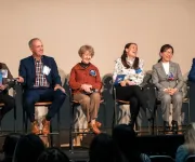 A stage of professional panelists smiling and laughing. 