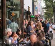  A lively crowd gathers outside Pearl Dive Oyster Palace, mingling and enjoying drinks along a bustling 14th Street sidewalk.
