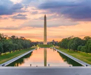 The Washington Monument glows at sunset with a colorful sky reflected in the Lincoln Memorial Reflecting Pool in Washington, DC.