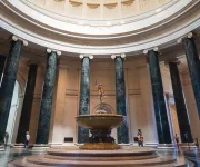 Grand rotunda of the National Gallery of Art featuring a circular fountain and towering marble columns.