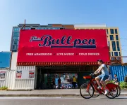 A cyclist rides past The Bullpen, an open-air venue near Nationals Park advertising live music, cold drinks and free admission.