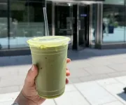 A hand holds up a to-go matcha