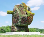 Jeff Koons’s “Split-Rocker” is a massive floral sculpture shaped like a rocking horse head, covered in colorful blooming plants.