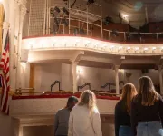 A group of people stand on stage, looking up into the box seating section of the historic Ford's Theatre.