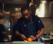 Chef in a dim kitchen preparing food under warm task lighting