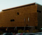 Modern brown building at dusk and traffic passing by