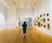 Person walking through bright art gallery in The Phillips Collection with framed works on white walls