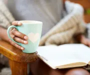 Woman holding mug and reading a book