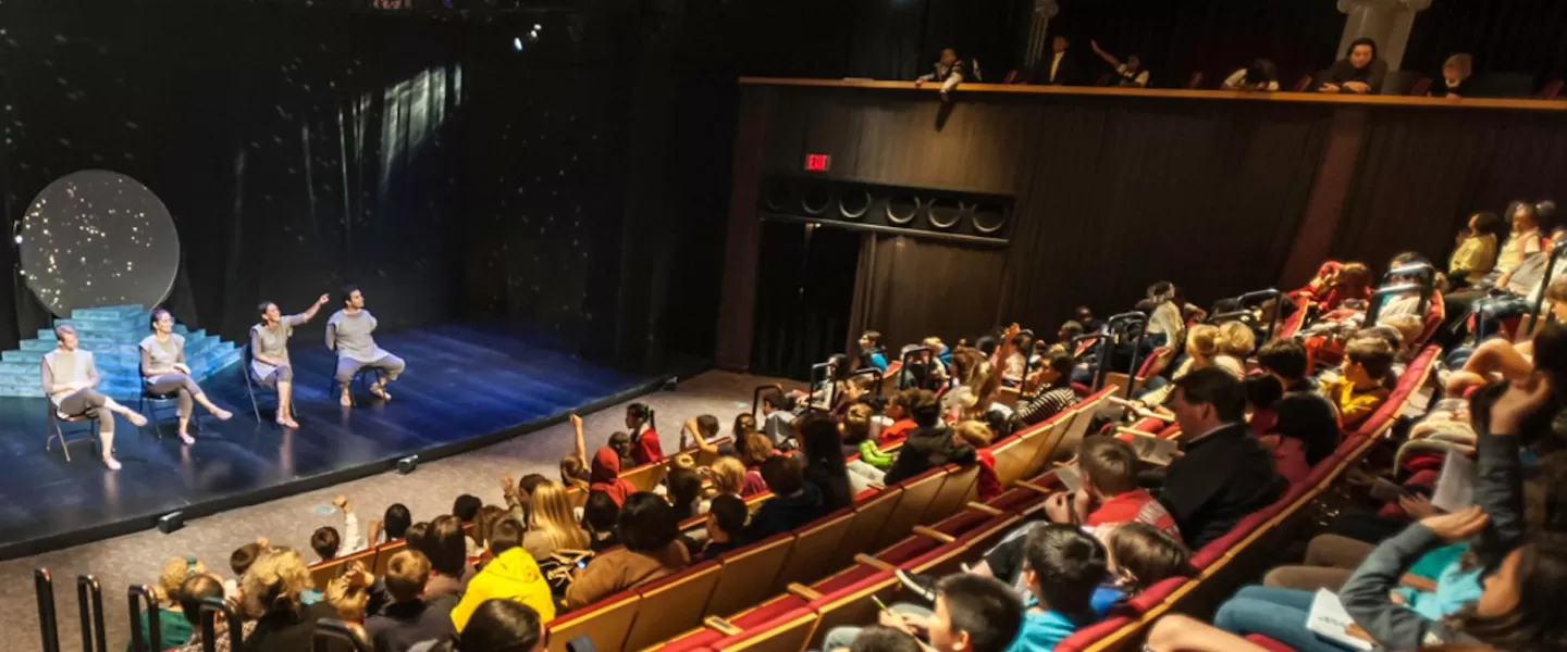 Audience watching a performance on stage with four actors.