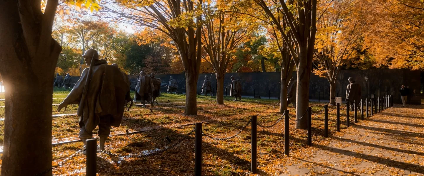 The Korean War Veterans Memorial in evening light with autumn trees and leaves on the ground. 