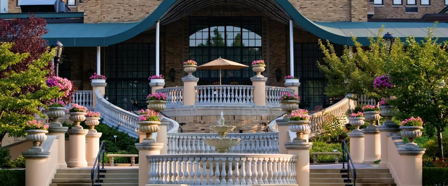 A grand staircase and terrace adorned with flower-filled planters lead to the elegant entrance of the historic Omni Shoreham Hotel in Washington, DC