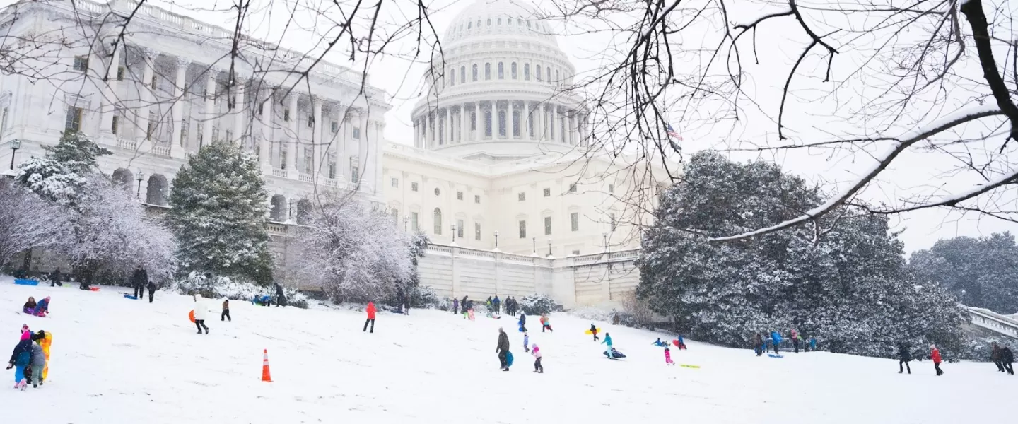 Families and children sledding on the snowy grounds near the U.S. Capitol in Washington, DC.