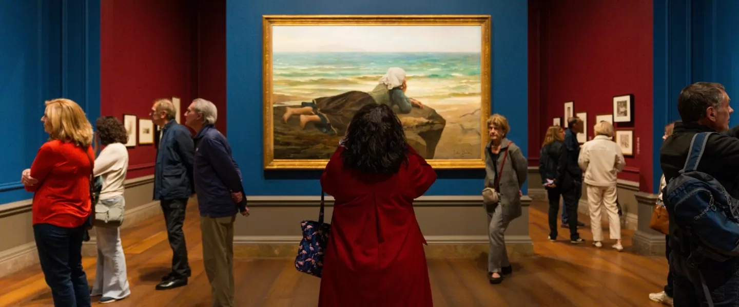 Bezoekers bewonderen een groot ingelijst schilderij in een kleurrijke galerij in de National Gallery of Art.
