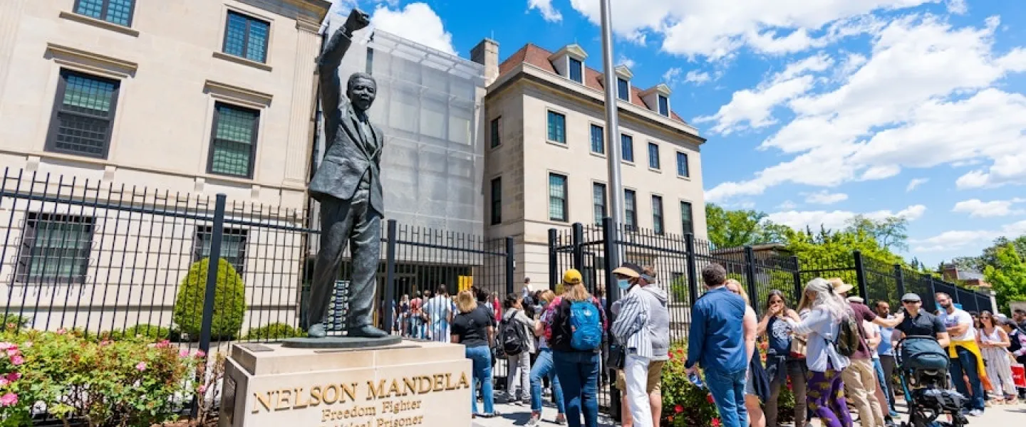 Visitors wait in line beside a statue of Nelson Mandela to enter the South African Embassy in Washington, DC. 