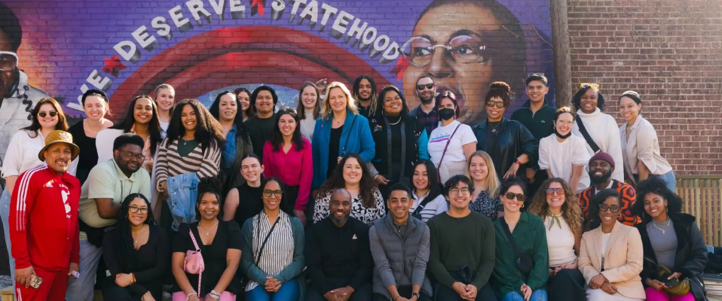 The Destination DC team sits in front of the Go-Go Museum in Washington, DC. Behind them, a mural says "We Deserve Statehood"