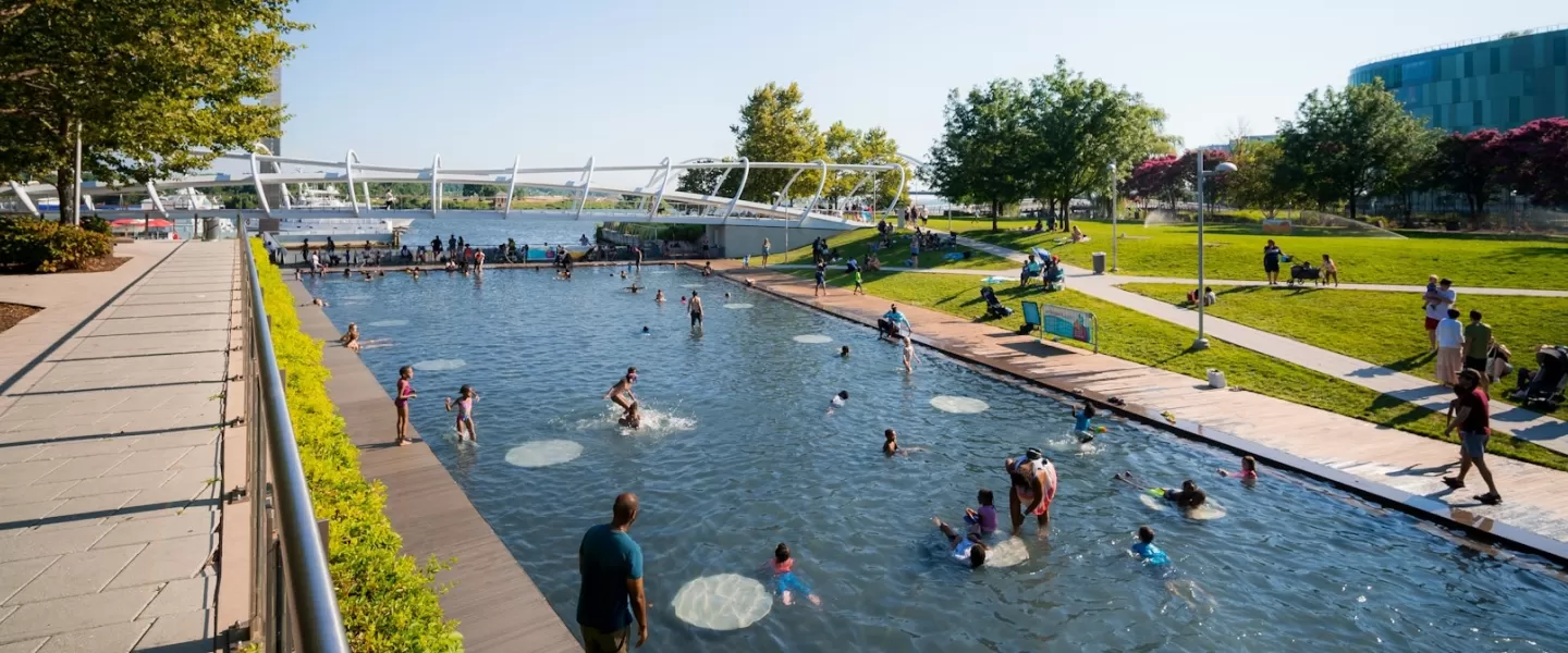 Des enfants jouent dans une immense piscine dans un parc public en été.