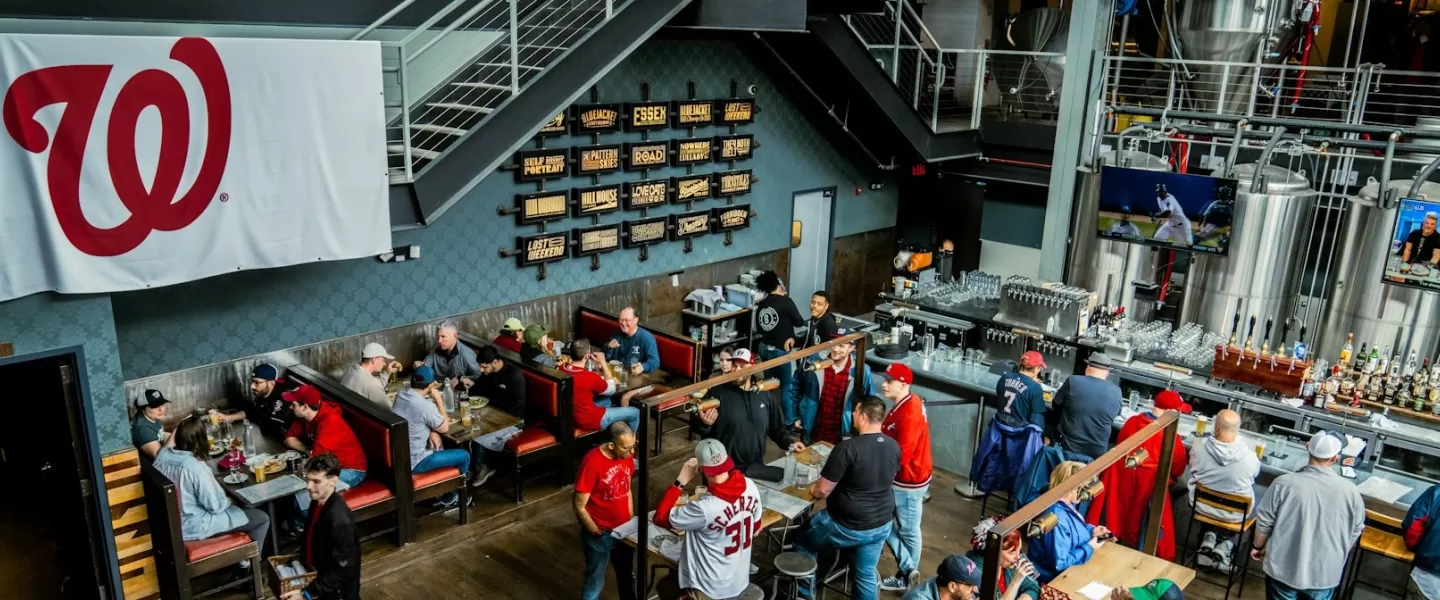 Interior de una cervecería repleta de productos de los Nacionales y gente con camisetas.