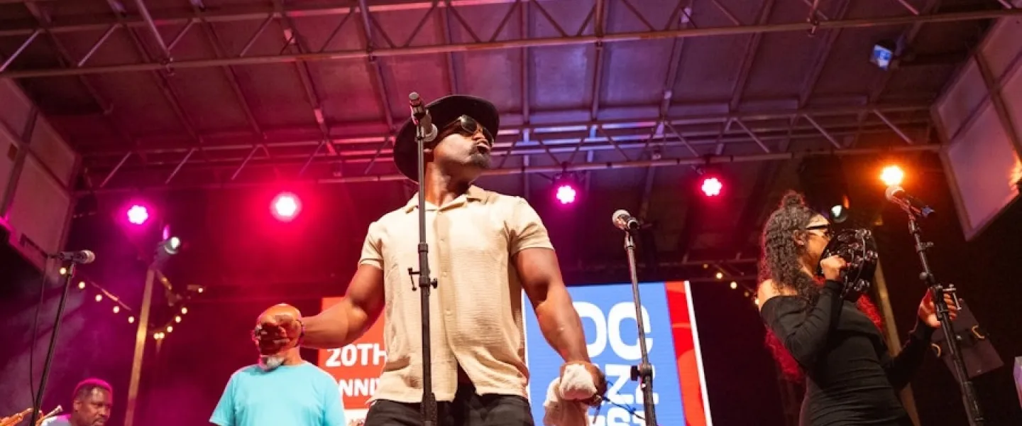 Musicians perform on stage under colorful lights at DC JazzFest.