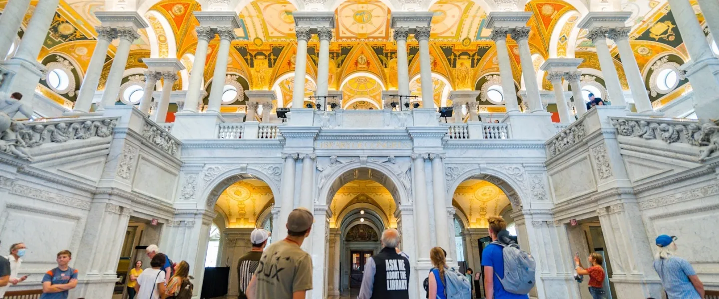Visitors look up at the ornate columns and golden ceiling inside the Library of Congress Great Hall.