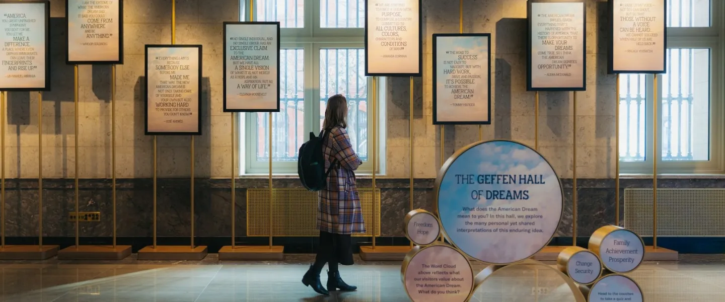 A visitor reads framed quotes in a museum gallery labeled “The Geffen Hall of Dreams.”
