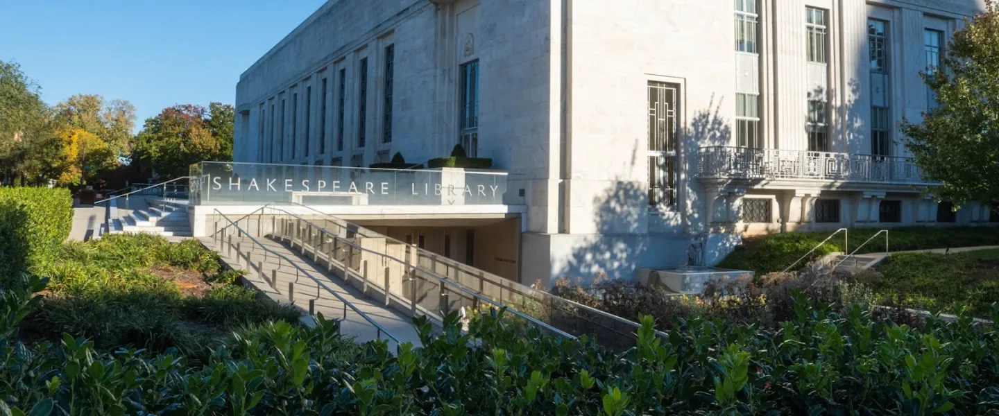 Modern concrete building with long ramp, surrounded by green shrubs and trees