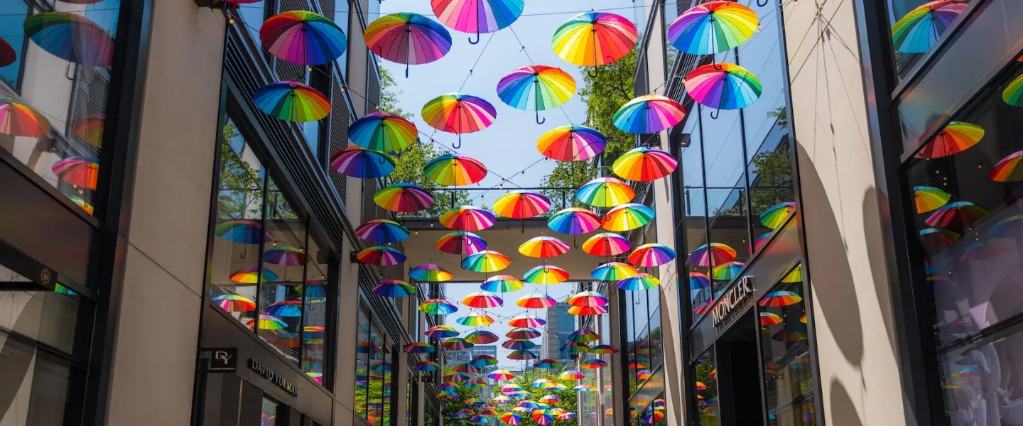 Colorful umbrellas hanging in a covered walkway between tall buildings
