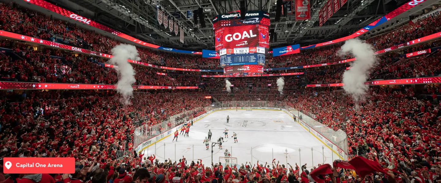 Hockey arena packed with fans, smoke jets and a “GOAL” scoreboard graphic over the ice