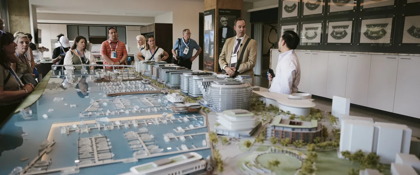 Visitors view a large waterfront city model in a museum gallery, with ships and bridges.