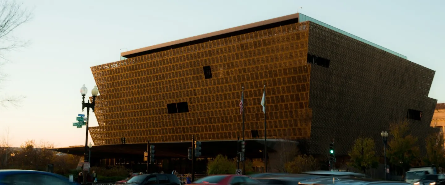 Modern brown building at dusk and traffic passing by